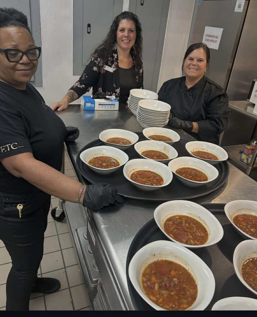 John 316 Center Taste Around the Lake 2025 team around a table in the kitchen with tray of soup